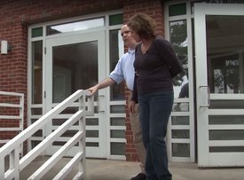 woman guiding a man down a set of stairs outside of a building